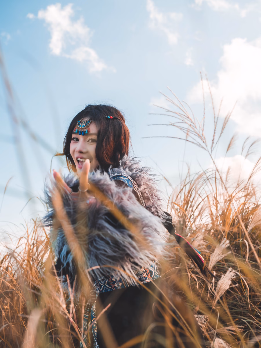 逆光芒草前的側身人像，藍天白雲