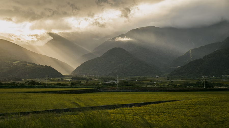 雲層下的中央山脈，光束落在山谷與稻田上