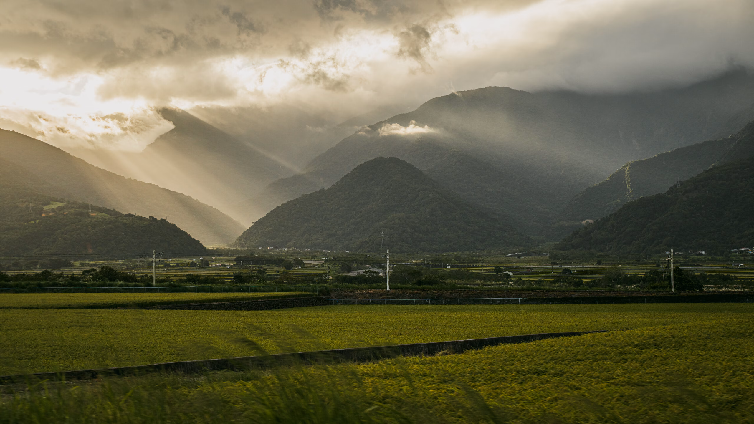 雲層下的中央山脈，光束落在山谷與稻田上