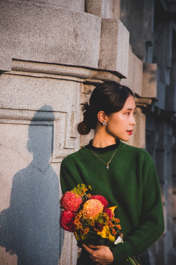 石牆前捧花回頭的女子