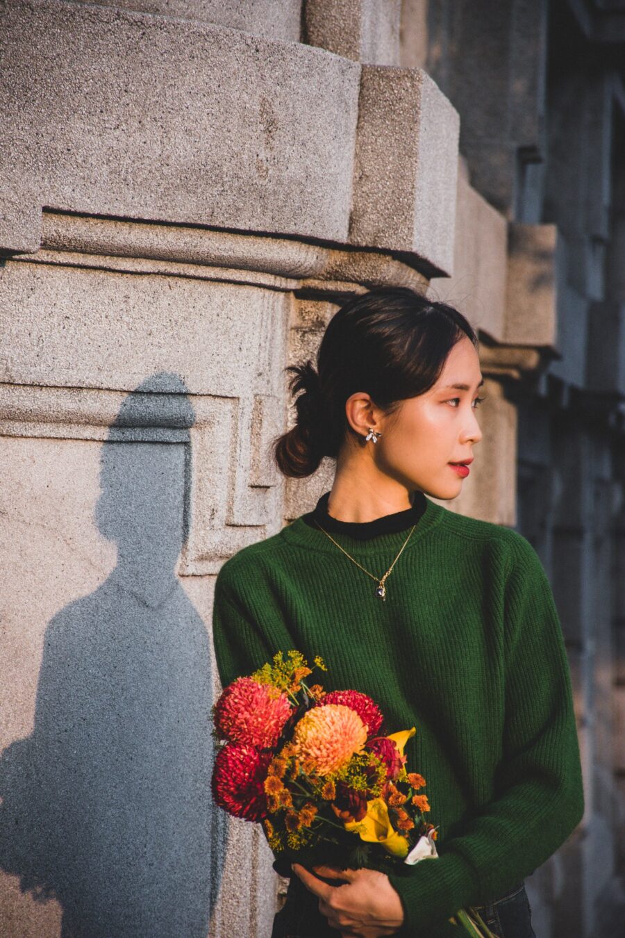 石牆前捧花回頭的女子
