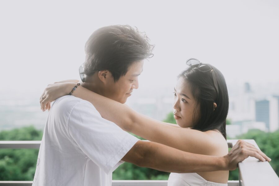 欄杆邊,男生摟著女生,背後是綠色山坡