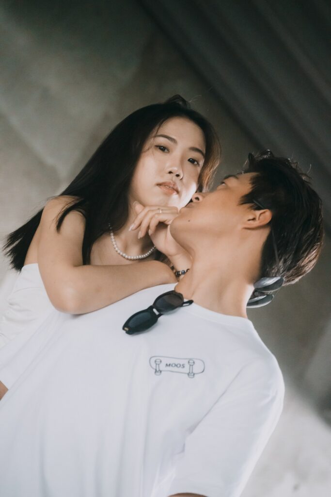 女生仰頭靠在男生肩上，背景是灰色混凝土