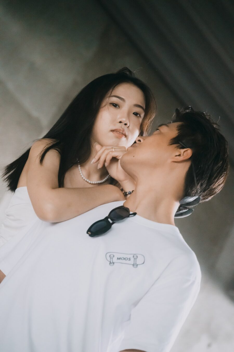 女生仰頭靠在男生肩上,背景是灰色混凝土