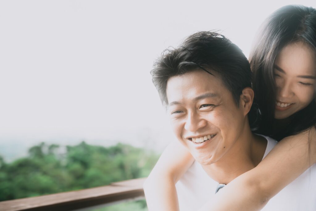 男生笑著回頭，女生從身後抱住他