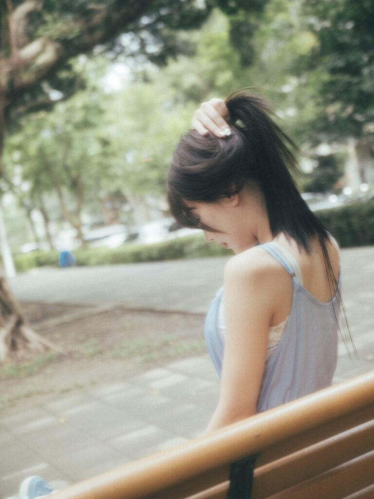 長椅邊側身低頭的女子