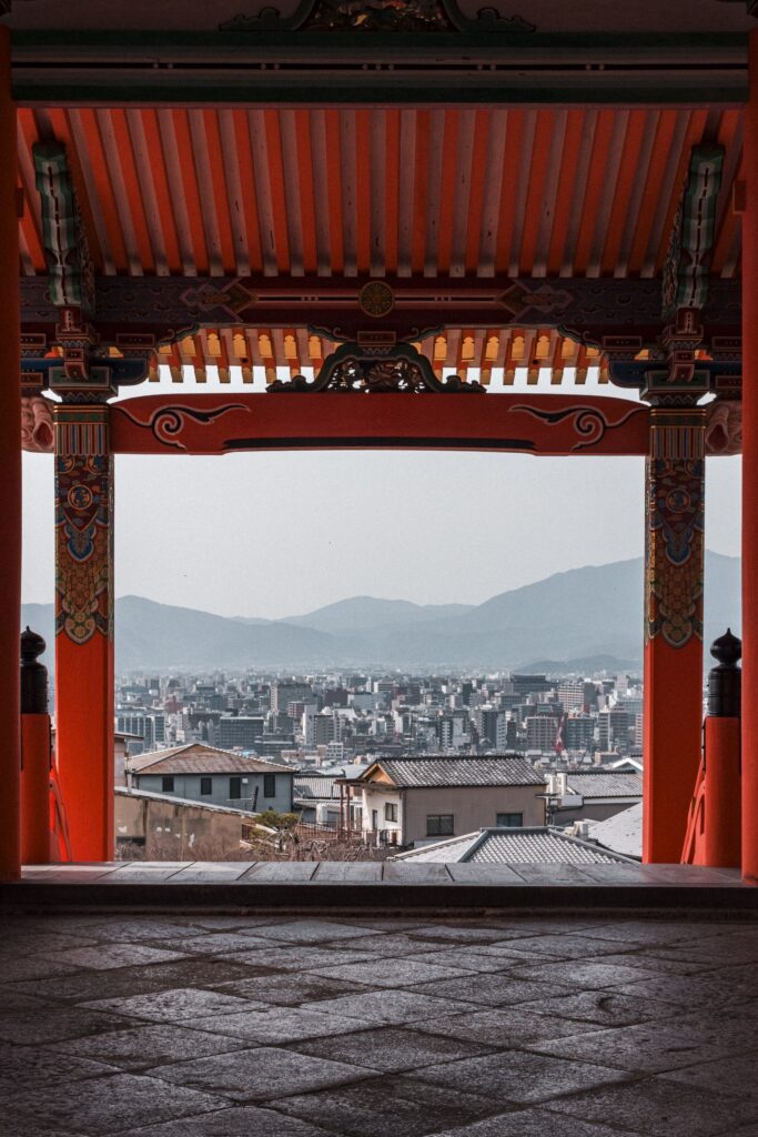 從朱色門柱之間望出去，框住遠方的京都市區與山
