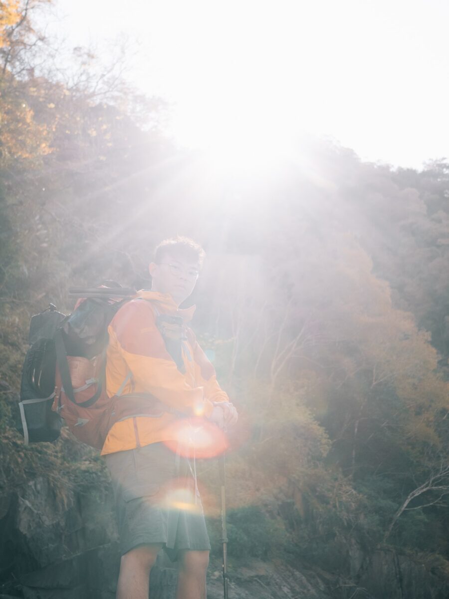 逆光中穿橘色外套的登山者