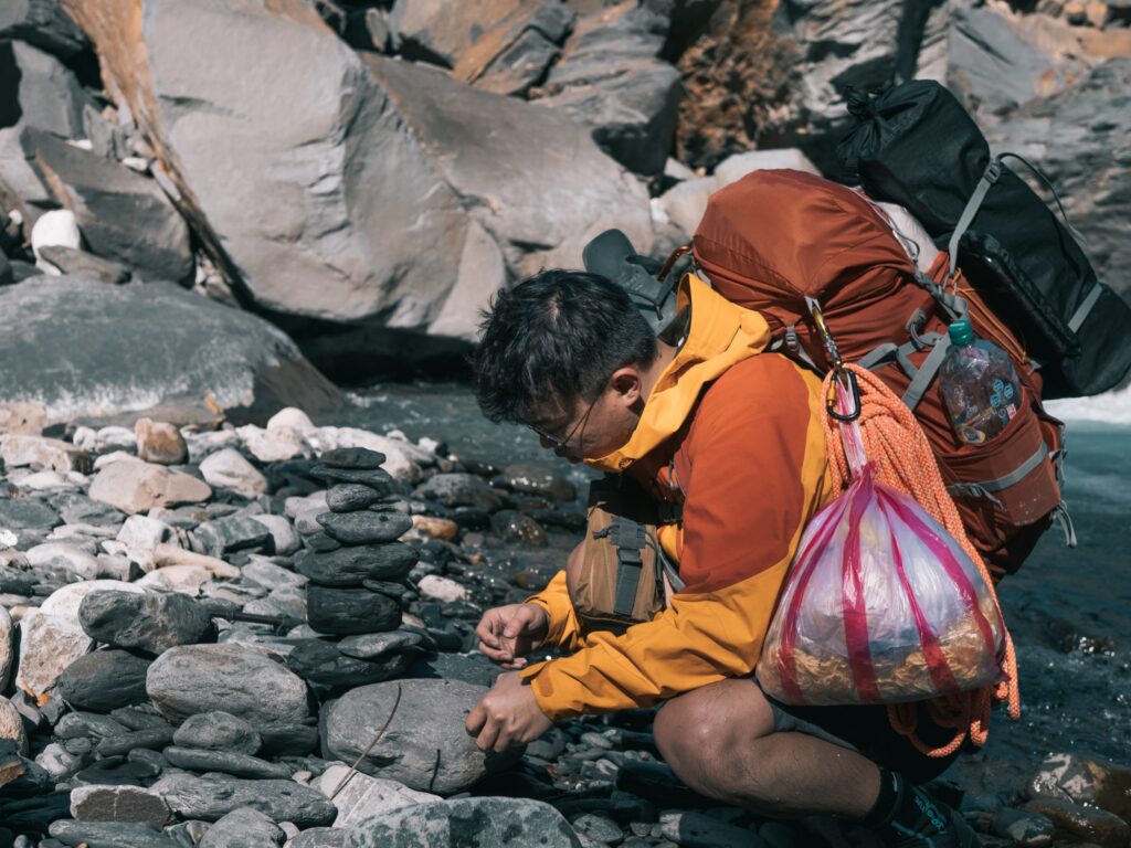 在亂石間彎腰整理背包的登山者