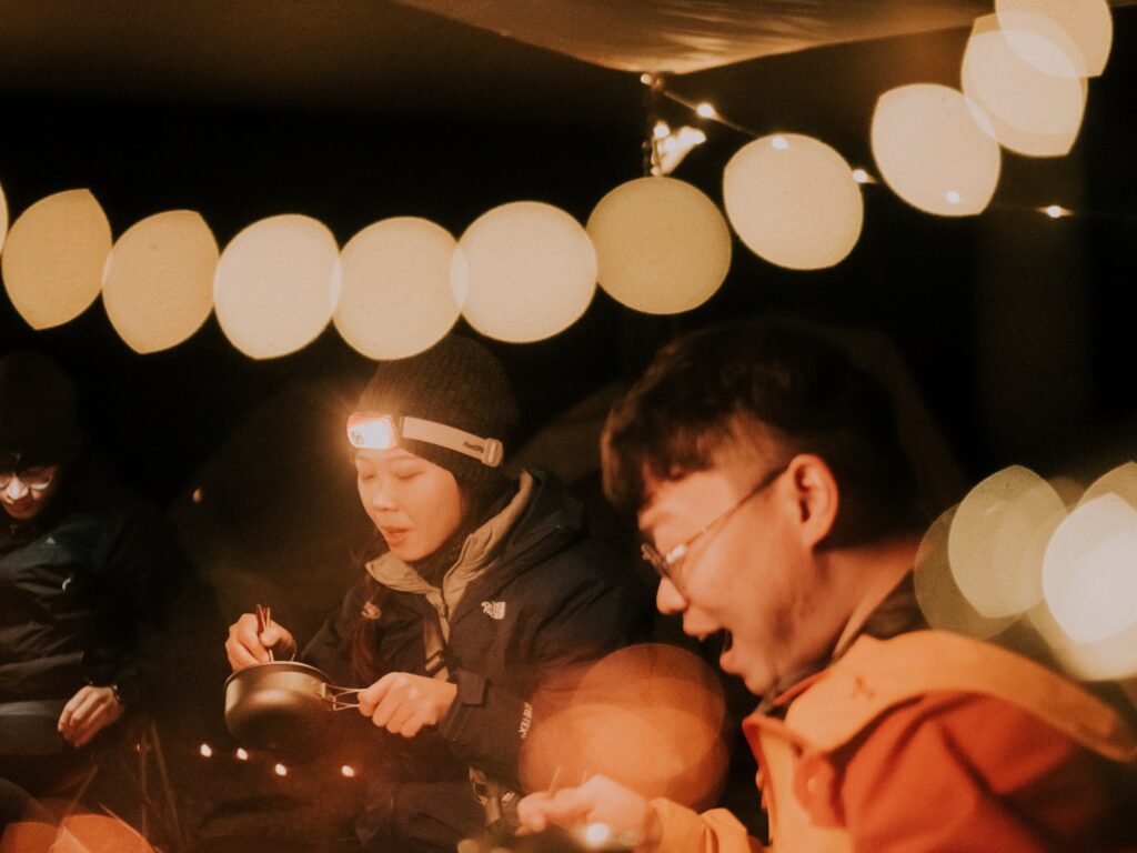 夜裡掛著燈串的營地，大家圍著吃飯
