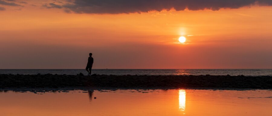 夕陽落在海平線上,一個人走過