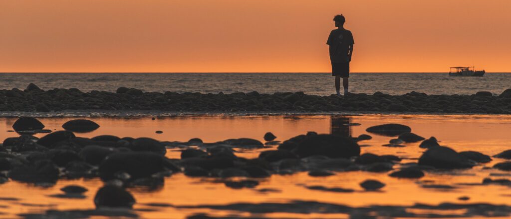 夕照中站在礁石上的人